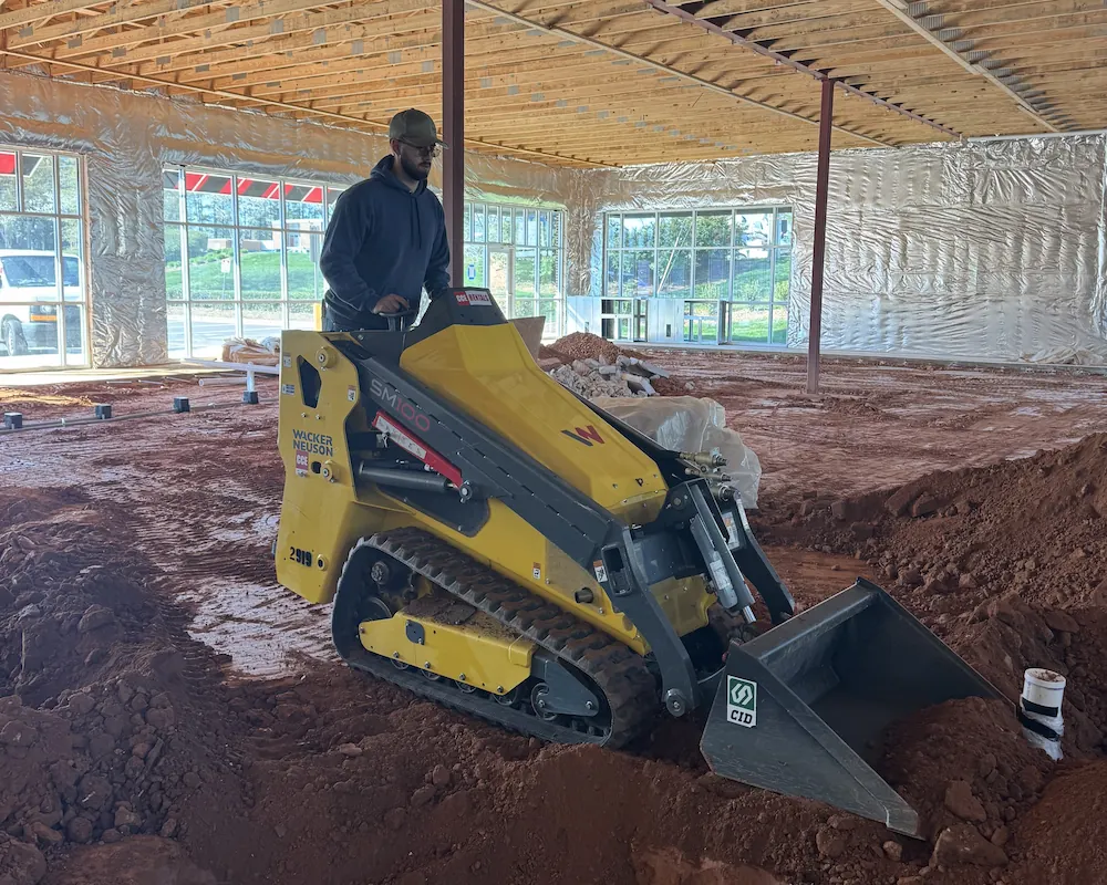 An Open Water Plumbing crew member grading a floor on a commercial fit-out