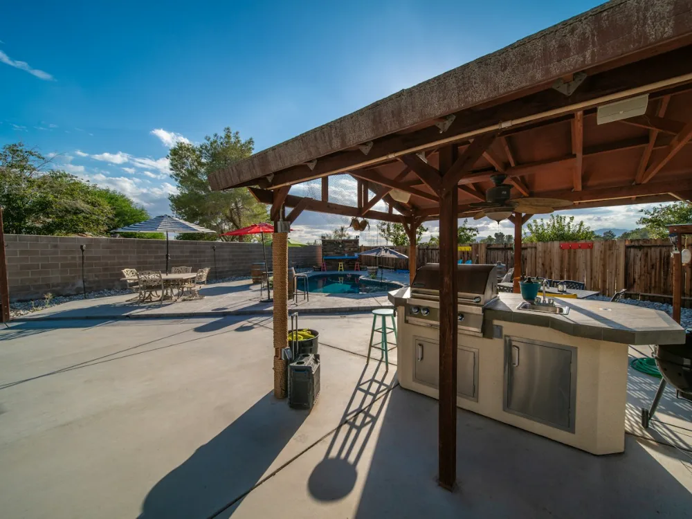 Covered outdoor kitchen and bar beside a swimming pool